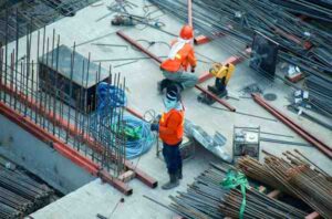 Are Headphones Allowed on Construction Sites and Job Sites? Construction worker near heavy equipment with safety PPE